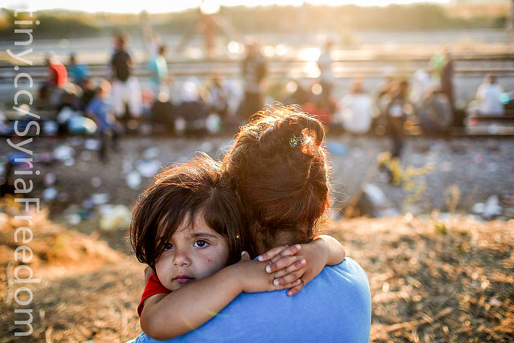 A young Syrian migrant girl is held by her mother next to railroad tracks where migrants wait to cross into Macedonia Sept. 2, in Idomeni, Greece. The number of people leaving their homes in war torn countries such as Syria, marks the largest migration of people since World War II. (Win McNamee/Getty Images - via Flickr Commons)